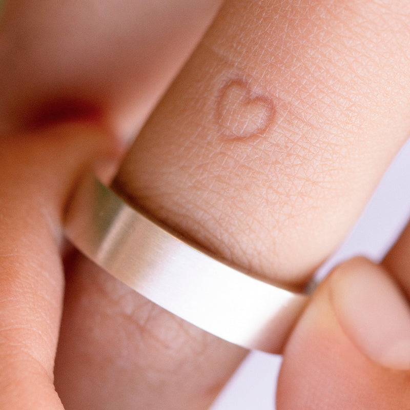 A photo displaying both the heart-shaped impression left on the finger and the Inner Message ring with a heart embossment